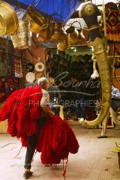 Image du Maroc Professionnelle de  Dans cette ancienne rue des teinturiers du souk de la ville touristique du Maroc, un ouvrier traverse l’espace à grande vitesse chargé de laine récemment colorée en rouge, le 10 Avril 2004.  (Photo / Abdeljalil Bounhar)